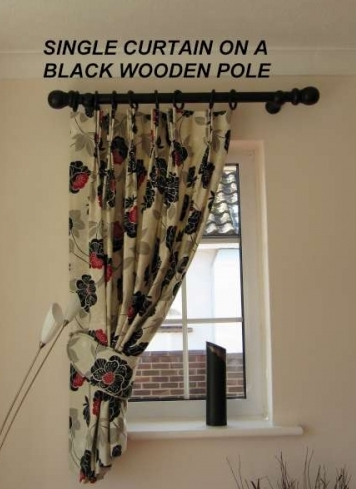 Made to measure wooden curtain pole in a small window with single curtain and piped tie back in Ferring, West SussexSingle Curtain On A Black Wooden Pole