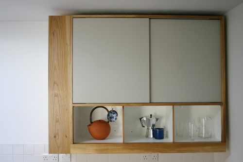 Kitchen wall cabinet with english elm framing and sliding doors clad in formica